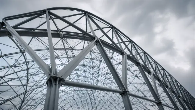 Vista inferior de estructura metálica industrial contra nubes