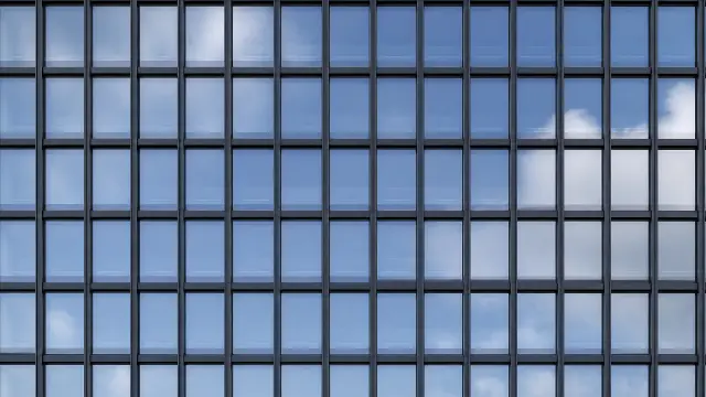 Fachada de cristal reflejando el cielo azul y nubes