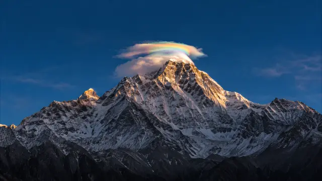 Nevado con arcoiris sobre cumbre majestuosa al amanecer