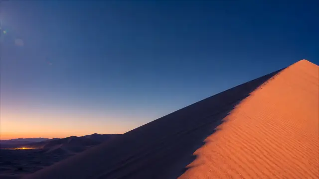 Dunas de arena al atardecer con cielo azul profundo