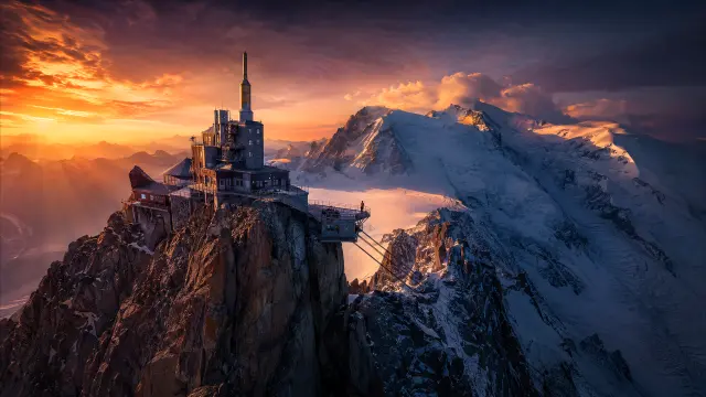 Edificio en la cima de una montaña nevada al atardecer