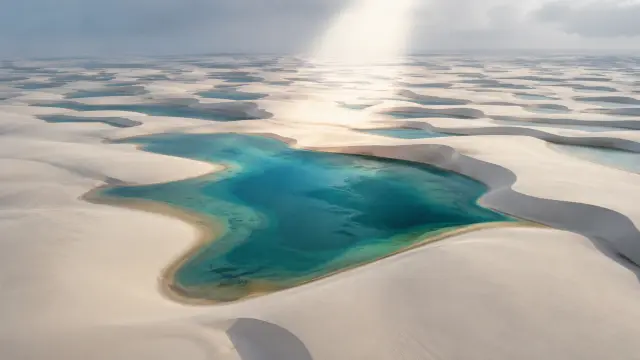 Lagos turquesa entre dunas blancas bajo rayos de sol