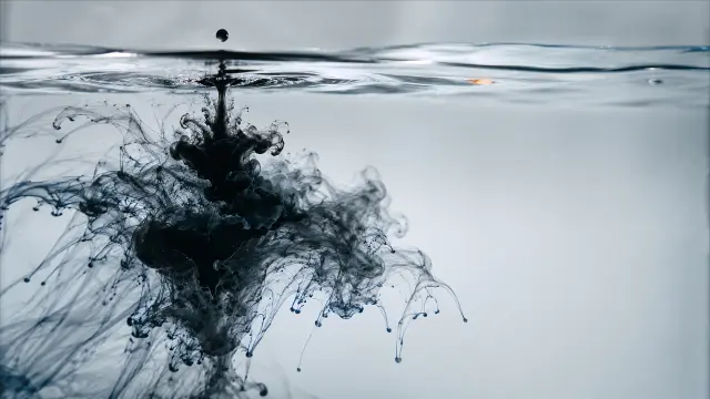 Gota de tinta negra expandiéndose en agua clara