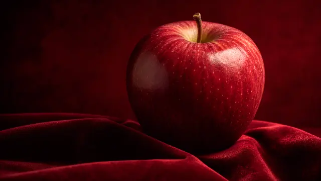 Manzana roja sobre tela de terciopelo rojo profundo