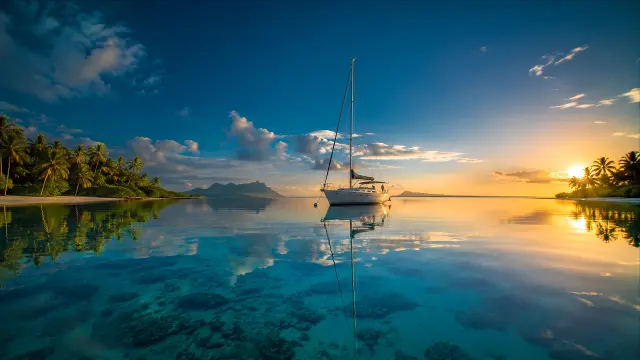 Yate blanco en calma tropical al atardecer con reflejos