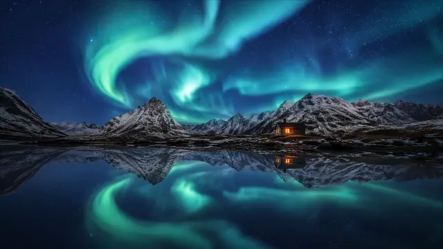 Aurora boreal y cabaña reflejada en un lago