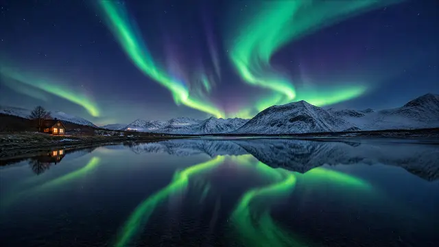 Aurora boreal verde sobre lago y montañas nevadas