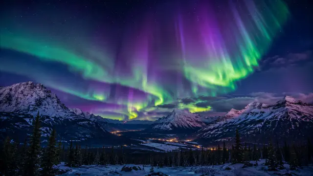 Aurora boreal sobre montañas nevadas y valle nocturno