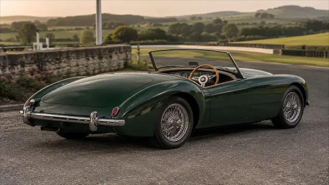 Coche clásico verde en carretera de campo al atardecer