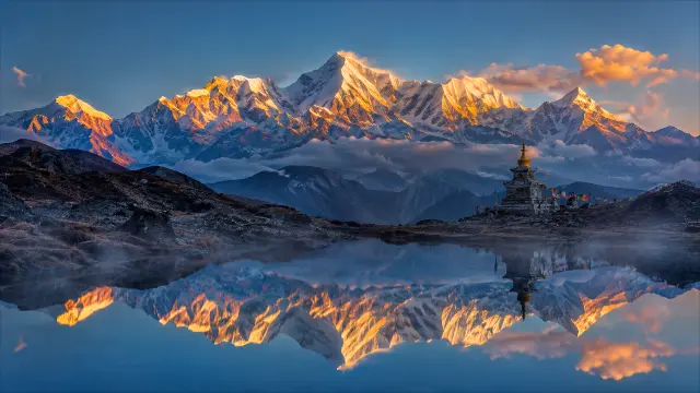 Montañas nevadas reflejadas en lago con estupa