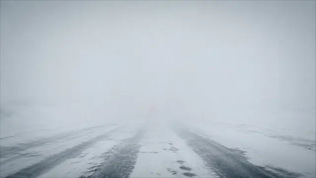 Tormenta de nieve y coche en carretera