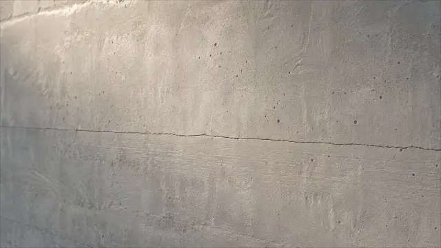 Textura de concreto gris con grieta horizontal y agujeros en la pared