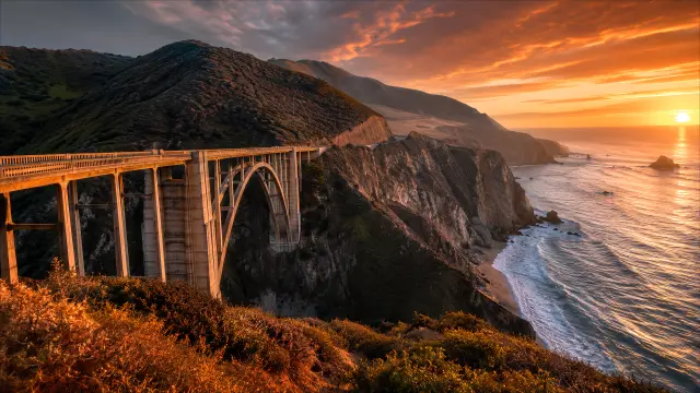 Puente costero en atardecer dorado sobre el océano